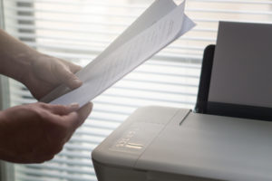 businessman-holds-documents-in-front-of-the-printer